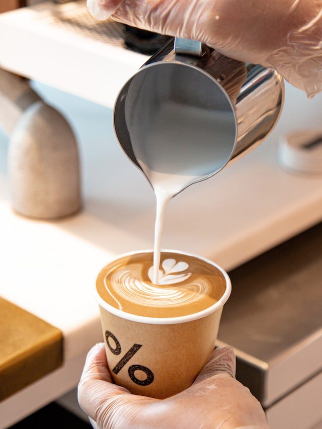 Man pouring milk into a cup of coffee