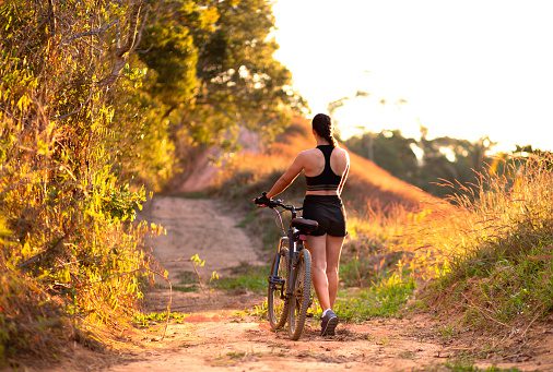 Woman climbing a trail with her mountain bike while enjoying nature