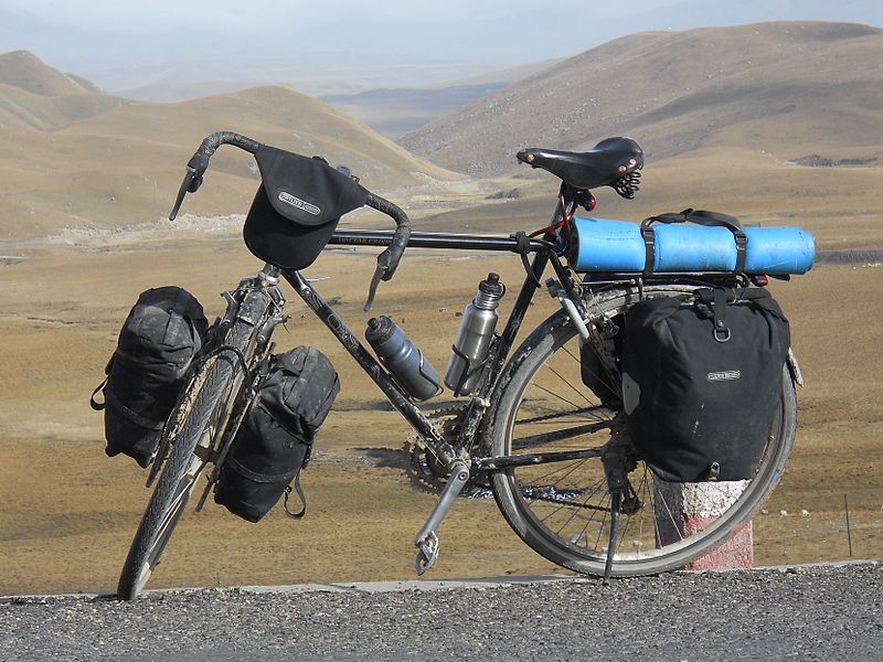 A loaded touring bicycle, with drop bars, 700c wheels, racks panniers and bar bag