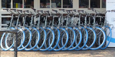 A rack of blue wheeled bicycles for rent