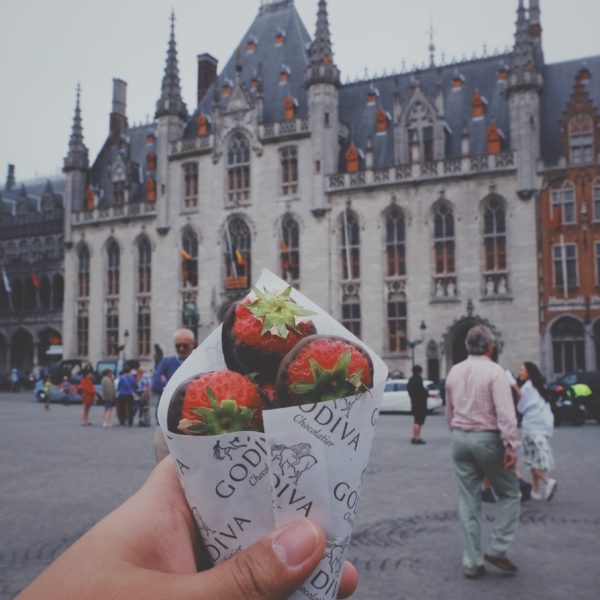 A person holding chocolate strawberries as they stroll in a city by Go to J Torres's profile J Torres - Unsplash