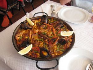 A paella pot on a dinner table with plates ready for serving