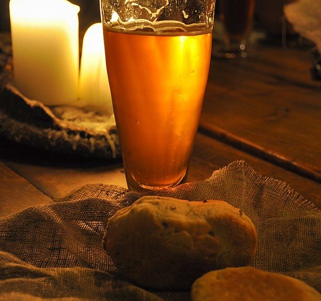 Medieval Dinner with beer glass, bread and candles lit background