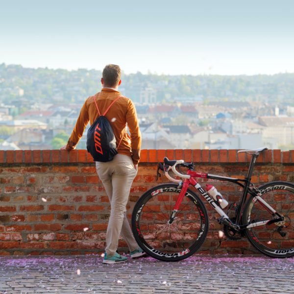 Man in casual clothes standing and watching the city view with a mountain bike beside him by Yury Kirillov - Unsplash
